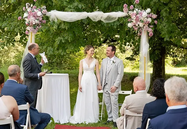 Freie Trauung unter Bäumen mit Blumenbögen