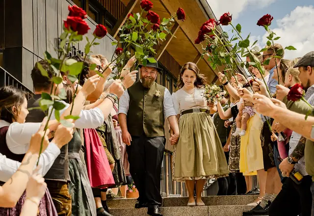 Brautpaar zieht durch ein Rosenspalier der Gäste